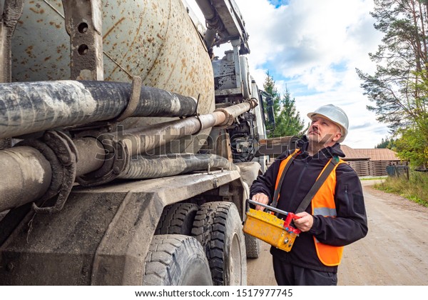 Cement truck. A man controls the flow of\
concrete. Delivery of concrete to the construction site. Remote\
control cement supply.\
Building.