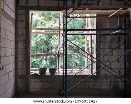 Cement tubs on the window sill with natural lighting and scaffolding on wet floor with block brick wall that did not plastering background