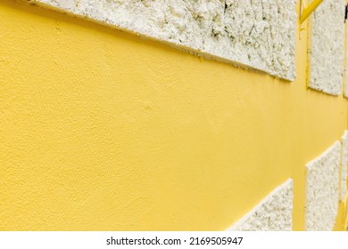 The cement wall is painted yellow and has white plaster.