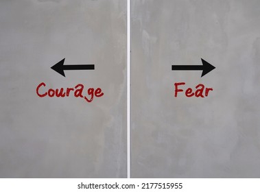 Cement wall with text and opposite direction to COURAGE or FEAR, choices to be brave and overcome fears - have the courage and step out from comfort zone