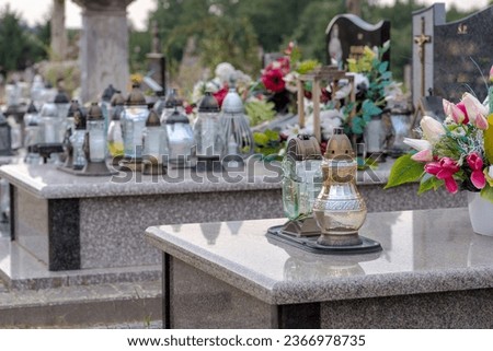 Cemetery - candles and flowers placed on granite tombstones.Final resting place. As an expression of memory of the deceased, candles and colorful flowers are placed on the graves.