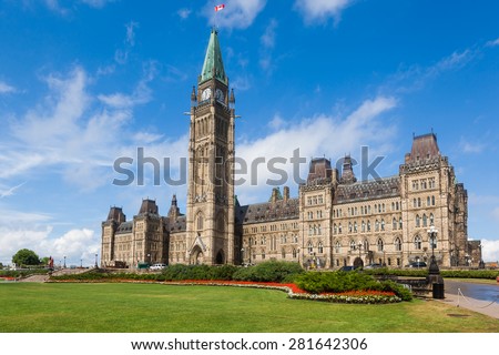 The Center Block and the Peace Tower in Parliament Hill, Ottawa, Canada. Center Block is home to the Parliament of Canada. The central green lawn and the red flowers  front the iconic building.