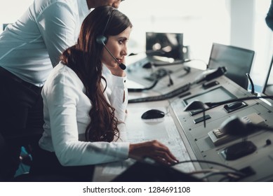Center of dispatching maintenance. Side on portrait of young brunette woman in white shirt working via headset on navigation controller board - Shutterstock ID 1284691108