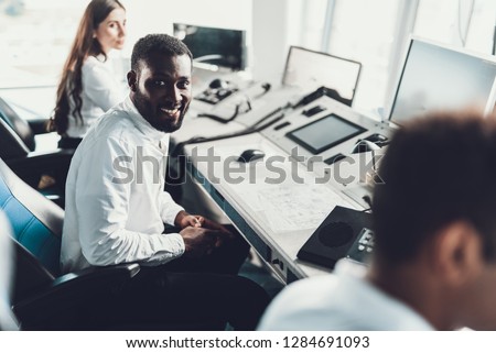 Center of dispatching maintenance. Top angle of young afro-american smiling male turning on while sitting on air navigation controller board