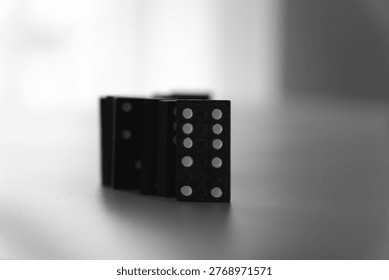A centered vertically aligned row of dominoes on a white surface in a s curved pattern