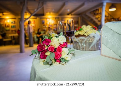 Centerpiece made of green leaves and fresh flowers stands on the dinner table. Wedding day. Fresh flowers decorations. Peach and awhite weddnig decorations.