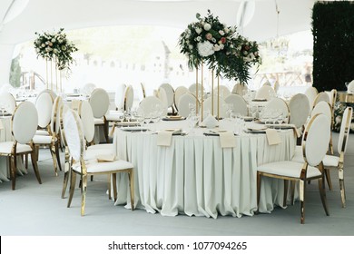 Centerpiece Made Of Green Leaves And Roses Stands On The Dinner Table Number Eight