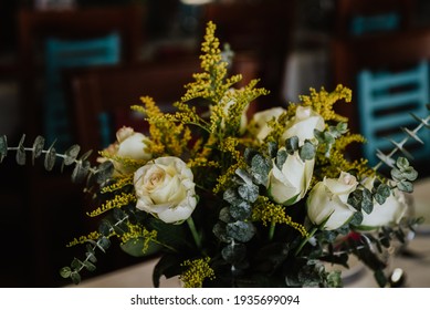 Centerpiece With White Roses, Eucalyptus, And Yellow Flowers
