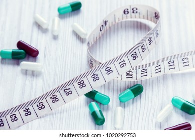 centimeter and pills, closeup, on white wooden background
