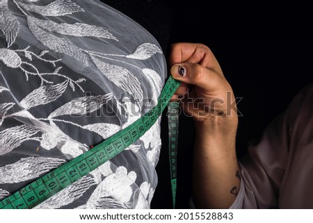 A centimeter is a tailor's tool for measuring when sewing - Close-up of sartre's hands taking measurements.