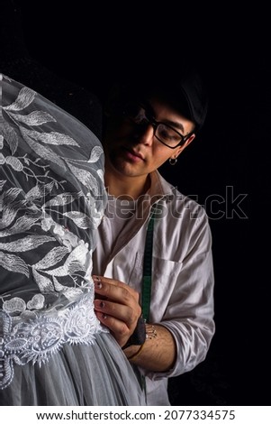 The centimeter is a tailor's tool for measuring when sewing - Portrait of a young fashion designer taking measurements with his tape measure.