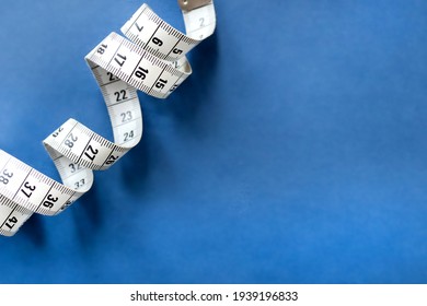 Centimeter tape, fitness and weight loss. Tailor's meter, for sewing, on a blue background. Meter, tape measure, to measure the body, waist in centimeters. - Shutterstock ID 1939196833