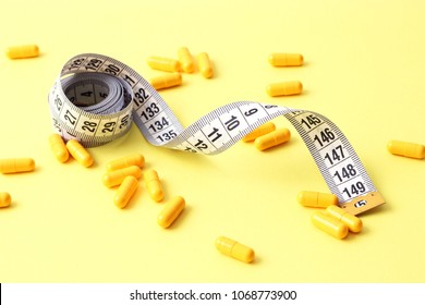 centimeter tape and pills on a colored background with space for text. concept of losing weight, diet, fat burning, healthy eating. minimalism.  - Powered by Shutterstock