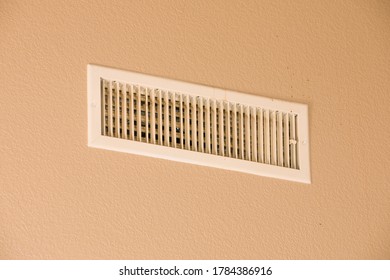 Central Air Conditioner Vent On A Beige Wall. Some Dust Build Up Evident When Zoomed In. Captured In An American Home.