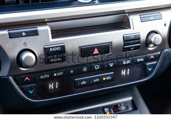 The central control\
console on the panel inside the car close-up with climate control\
and audio system and a hole for the CD and emergency button in gray\
and black.
