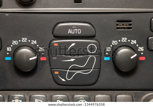The central control console on the panel inside\
the car close-up with climate control and audio system and a hole\
for the CD and emergency button in gray and black. Auto service\
industry. Comfort.