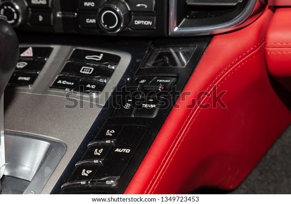 The central control console on the panel inside\
the car close-up with climate control and audio system and a hole\
for the CD and emergency button in gray and black with red leather\
interior