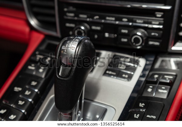 The central control console on the panel inside\
the car close-up with climate control and audio system and a hole\
for the CD and emergency button in gray and black with red leather\
interior