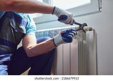 Central heating mechanic and handyman fixing home radiator, gas crisis and seasonal issues. - Shutterstock ID 2186679913