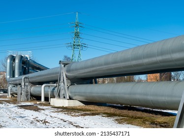 central heating pipes in a protective metal thermal insulation jacket laid above the ground on a sanny winter day