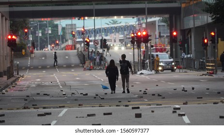 Central, Hong Kong - November 13, 2019: A Couple Walks Down An Empty Hong Kong Street With Bricks And Bamboo Sticks Scattered On It To Block Traffic 