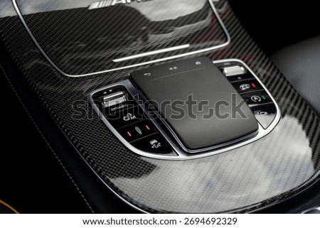 Central infotainment touch pad and multiple buttons on carbon fiber trimmed dashboard console inside an exclusive luxury sedan car