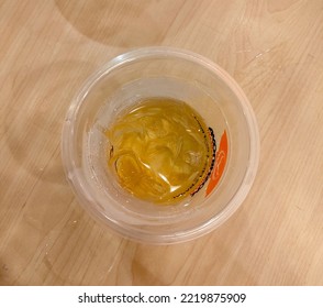 Central Jakarta, Indonesia - October 29th, 2022 - An Iced Ocha Green Tea In Plastic Cup, Almost Finished. From Japanese Restaurant, Yoshinoya. Top View, With Wood Table Surface As The Background.