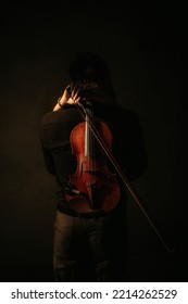 Central Java, Indonesia - August 24, 2022: A Woman Hugs A Man While Carrying A Violin In A Photo Studio