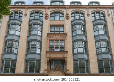 A central ornamental section divides rows of projecting bay windows on a Berlin facade. Symmetry, brickwork and decorative stone details define the historic building.