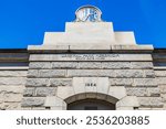 Central Park Reservoir South Gate House clock and stone facade with inscription, dated 1864, on clear day. New York. USA. 