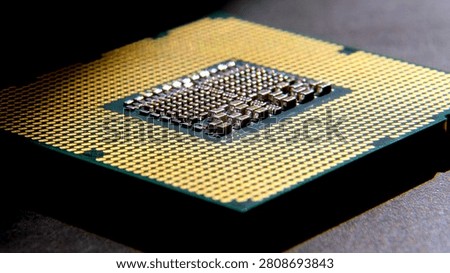 Central processing unit featuring gold pins and complex circuitry on a dark surface, highlighting modern computing technology and design intricacies
