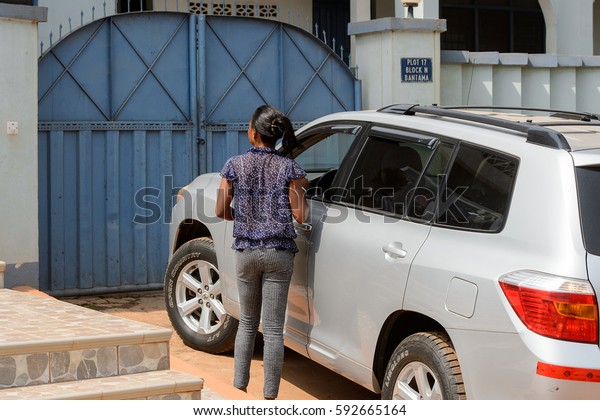 CENTRAL REGION, GHANA -\
Jan 17, 2017: Unidentified Ghanaian woman stands near the car from\
behind in local village. People of Ghana suffer  poverty due to the\
bad economy