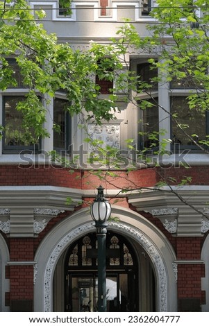 Central round-arch Romanesque style entrance on the red brick and rendered cement facade of a historic-heritage building from AD 1908 on the north side of Collins Street. Melbourne-VIC-Australia.