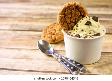 Ceramic bowl of banana ice cream dessert with chocolate and cookies, close-up on wooden background with copy space. Selective focus