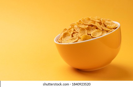 Ceramic Bowl Of Corn Flakes On Yellow Background With Copy Space