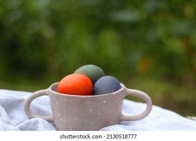Ceramic bowl filled with colorful Easter eggs in the garden. Selective focus. - Powered by Shutterstock