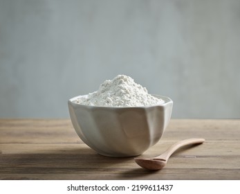 Ceramic Bowl Of Flour And Spoon On Wooden Kitchen Table