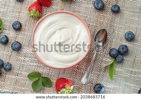 Ceramic bowl with plain yoghurt and berries on the table. Light summer mood.