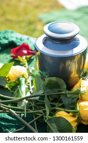 Ceramic Burial Urn Laid With Red And Yellow Roses, In A Bright Funeral Scene