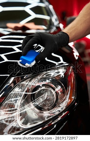 Ceramic Coating Application. Applying liquid glass sealant to black car hood for scratch resistance. Applying ceramic paint protection to restore and preserve vehicle aesthetics.