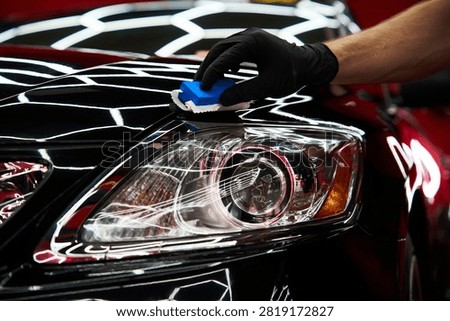 Ceramic coating application secures a black car hood by applying liquid glass sealant for scratch resistance and applying ceramic paint protection to restore vehicle aesthetics.