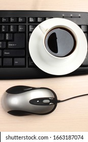 Ceramic cup with coffee and a computer keyboard on a wooden table