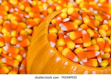 Ceramic Decorative Pumpkin Filled With Halloween Candy Corn. Closeup With Candy Corn Background.