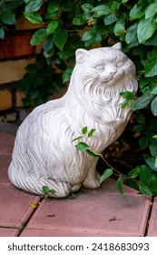 Ceramic decorative sculpture of a cat in a summer garden. Garden sculpture