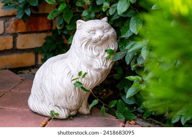 Ceramic decorative sculpture of a cat in a summer garden. Garden sculpture