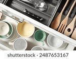 Ceramic dishware, utensils and cutlery in drawers, top view