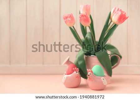Ceramic hen, Easter eggs and wase with tulips on pink wooden table. Easter celebration concept. Soft focus