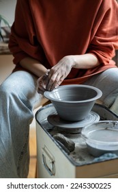 Ceramic master creating handmade stoneware on wheel in studio, making wheel-thrown ceramics, forming clay into shape. Mindful craft of pottery and art therapy concept