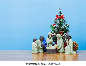 Ceramic Model Of Mary And Joseph With Three Wise Man Worship Baby Jesus Christ In Front Of Christmas Tree Over Blue Sky Background Show Christian Concept Jesus Is The Reason Of Season, Copy Space