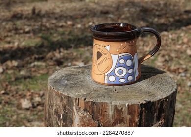 Ceramic mug with tea on a tree stump in a forest park